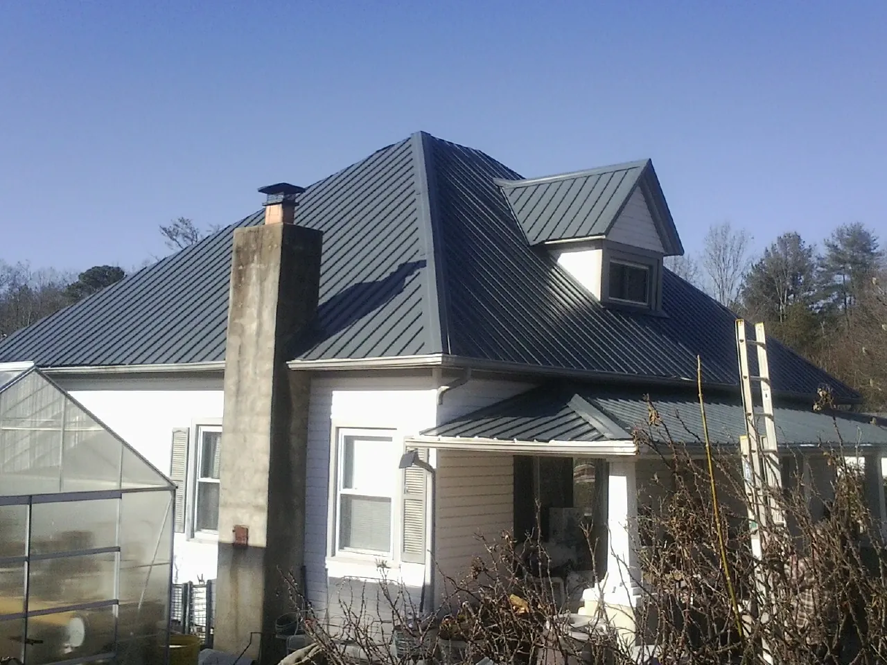 Dark blue standing seam metal roof on a white farmhouse with dormer — Slate & Tile Roof Repair by Roofing Brothers in Flower Mound