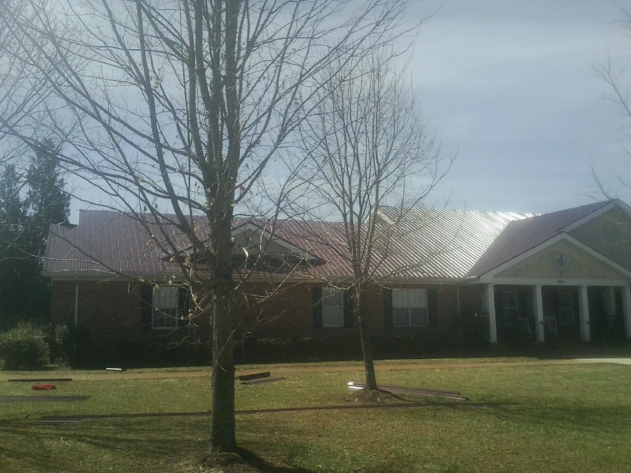 Red metal roof on a brick building seen from the front lawn in Flower Mound