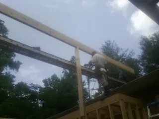 Carpenter setting a ridge beam over a new addition frame — Ice Dam Removal by Roofing Brothers in Flower Mound