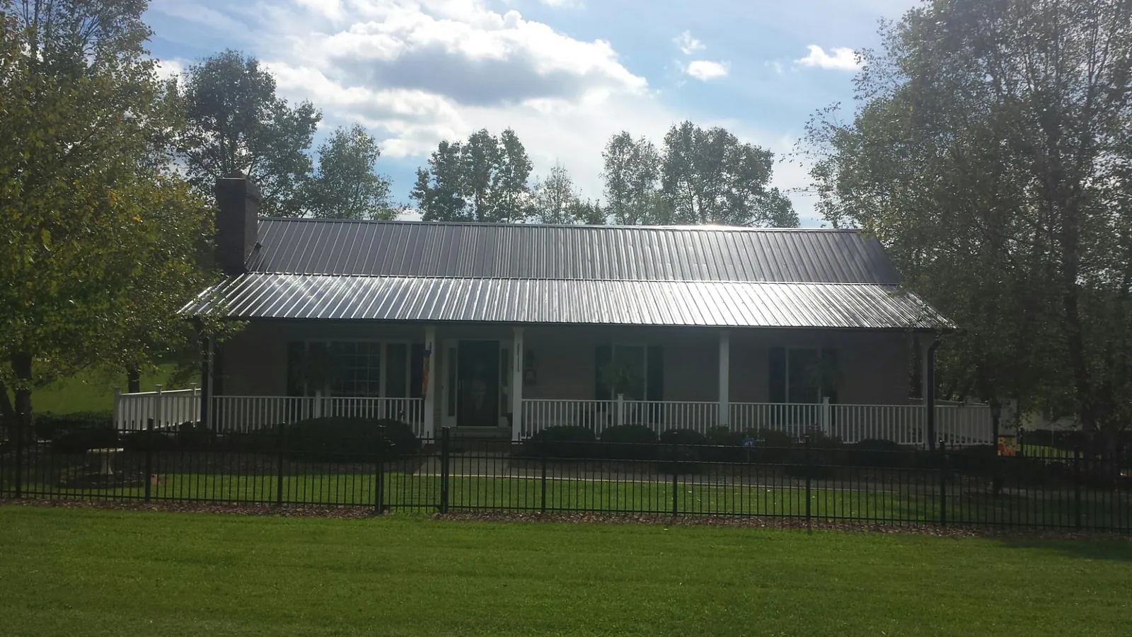 Gray metal roof on a brick ranch with a full width front porch — Gutter Guard Installation work by our crew in Flower Mound