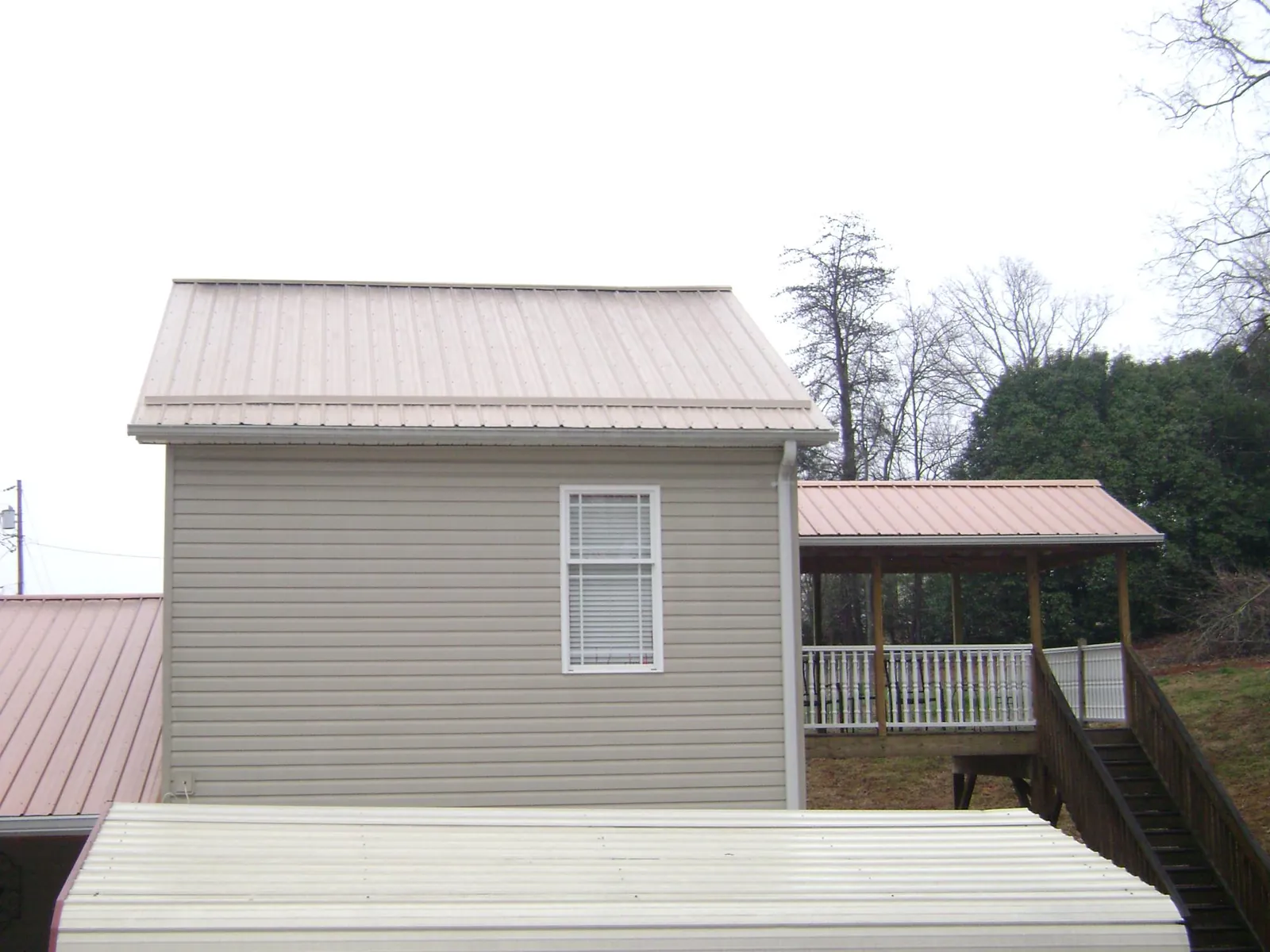 Tan metal roofs on a two story addition and attached porch, from a Roof Replacement job in Flower Mound
