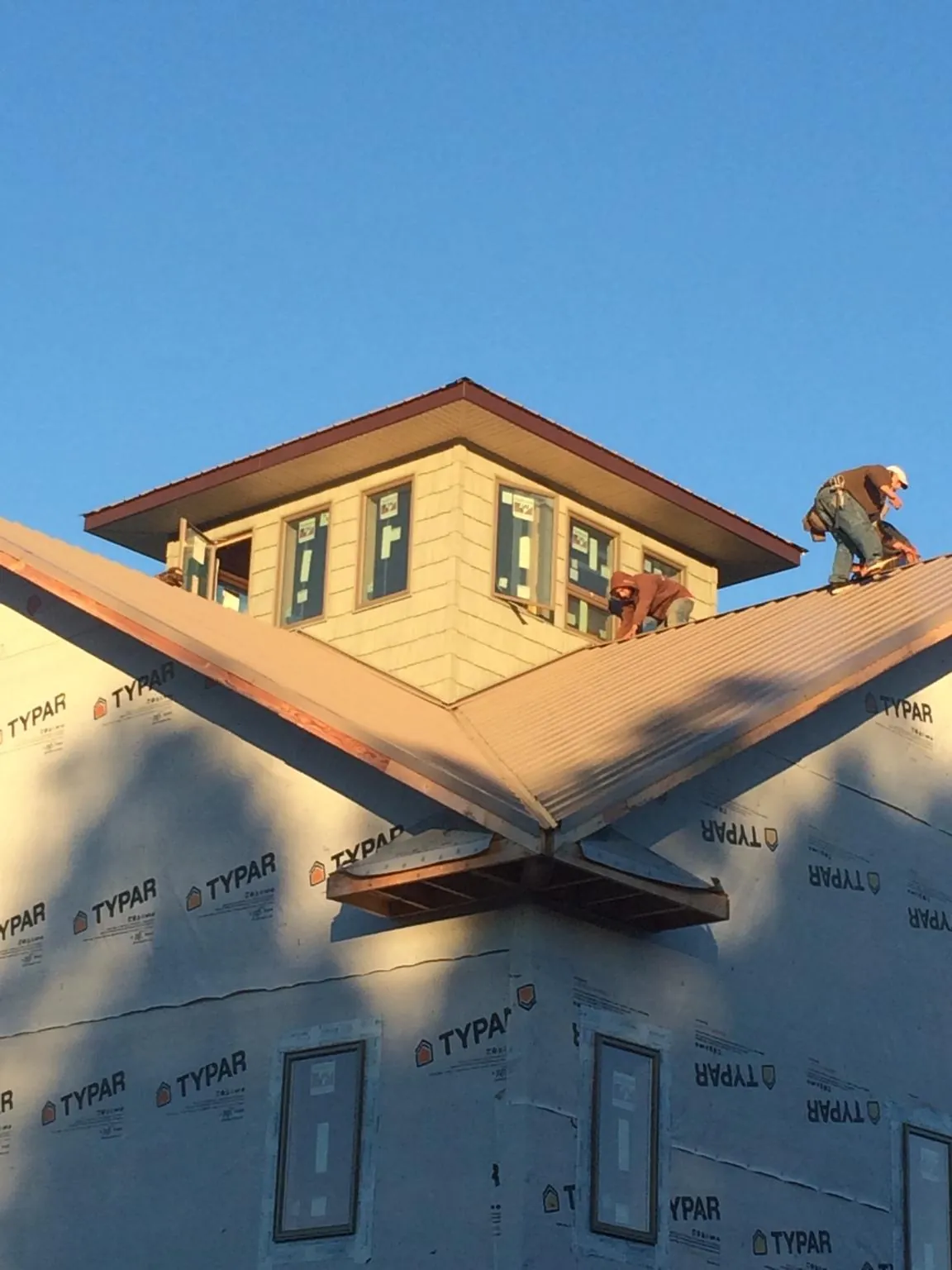 Roofers working around a rooftop cupola on a new metal roof at sunset — Roof Waterproofing in Flower Mound by Roofing Brothers